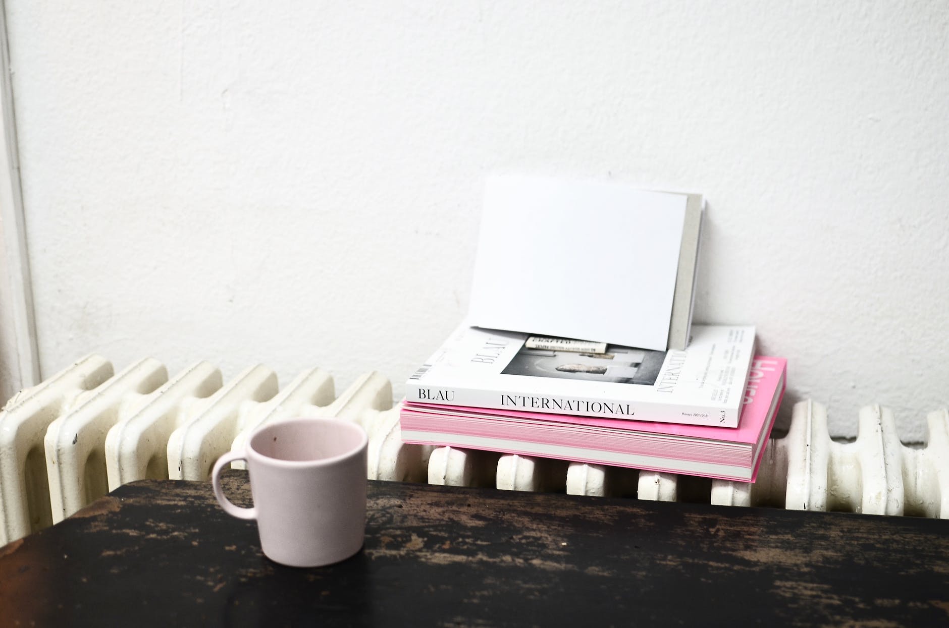 ceramic cup on table near radiator with books