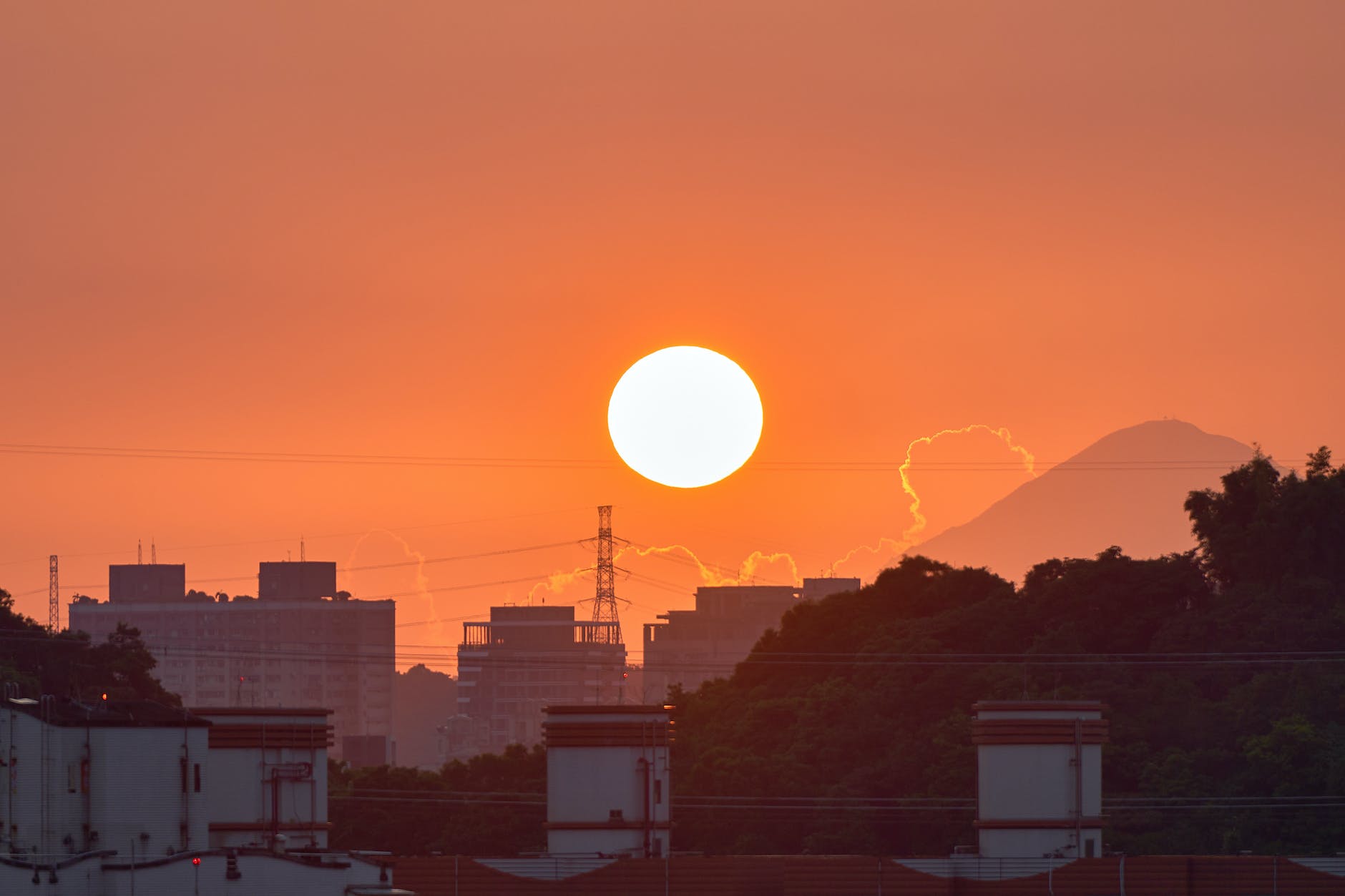 silhouetted city skyline and a mountain at sunset